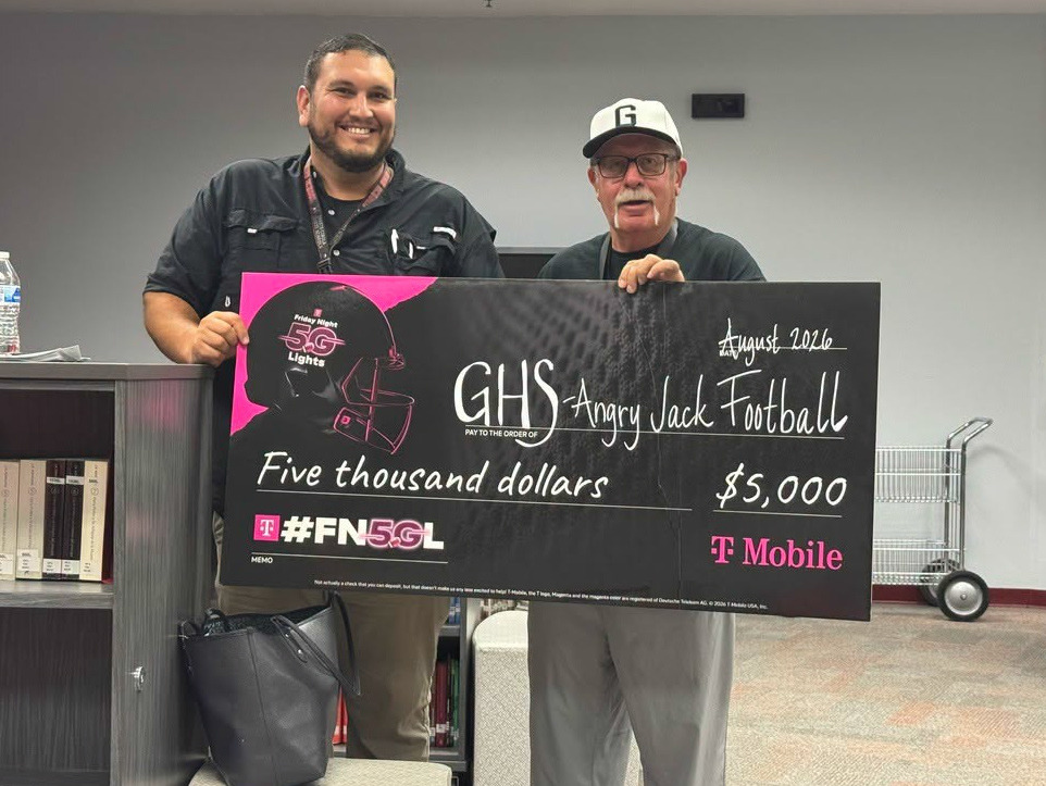 Grants High School Athletic Director Reyes Jaramillo, left, and head football coach Gene Reidinger display a ceremonial $5,000 check from T-Mobile’s Friday Night 5G Lights competition. The award will be used to purchase athletic and safety equipment for Grants High School student-athletes as the school remains eligible for larger prizes in the national competition. Courtesy Photo