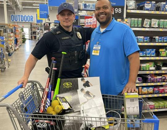 Milan Police Chief Carl Ustupski (left) and Walmart Store Manager James Hankins (right) prepare for checkout after MPD partnered with Walmart to update Milan’s youth tee-ball league’s equipment, including helmets, tees, bats, and balls. Read more about this community event on Page A7. Courtesy Photo — Carl Ustupski