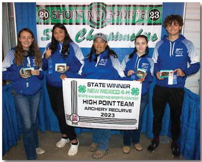 Courtesy Photo In the photo (from left to right), Sophia Bassett, Adrianna Landschoot, Coach Anna Cruz Landschoot, Richelle Villalobos, and Ralph Ortega. Photo depicts the Archery Team with their state banner after winning first place at the New Mexico 4-H Shooting Sports Championship.