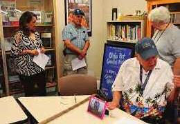 In this file photo by Kylie Garcia, Donn Webb is seen reaching for a record, surrounded by those interested in learning more about music. Webb was always happy to share his wealth of musical knowledge with anyone that would listen. Courtesy Photo
