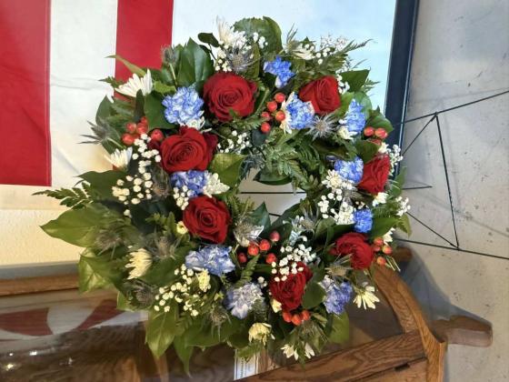 A red, white and blue wreath designed by Grants FFA members stands beside the American flag inside the Double Six Art Gallery during a Veterans Day luncheon honoring local service members. Courtesy Photo