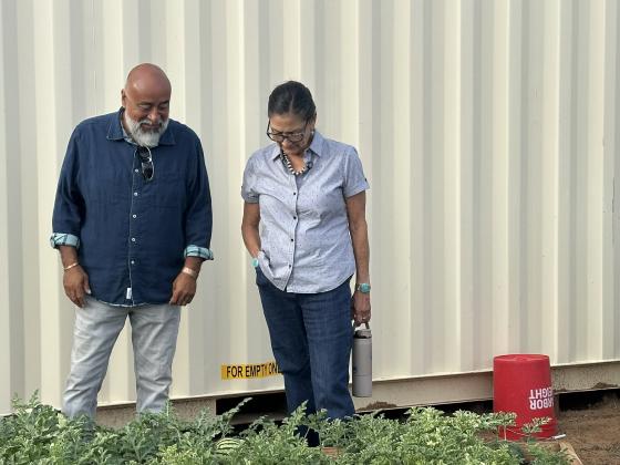 Grants Community Pantry garden master Donald Jaramillo shows Deb Haaland watermelons growing in the pantry’s Community Garden during her Aug. 21 visit. Haaland toured the garden beds as Jaramillo explained the crops being grown and the work behind the pantry’s expanding garden operation.