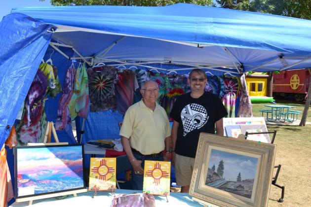 GRANTS, NM – Former Cibola Arts Council President, John Martinez, keeps new Director Eric Sedillos company as they man the Arts Council booth at the Fire and Ice Park on Friday, the opening day of Cibola Trail Days. Kathryn Marmon - CC