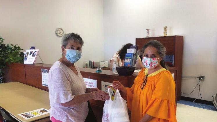 Shirley Gonzales (left) picked up her Grab-and-Go meal from the Cibola County Senior Citizens Center in Grants, N.M., on July 28. Genie Chavez (right) helped deliver the meal at the front of the center. The Grab-and-Go meals are an initiative by the New Mexico Aging and Long-Term Services department to address the critical food insecurity needs of the Cibola County community. Diego Lopez -CC