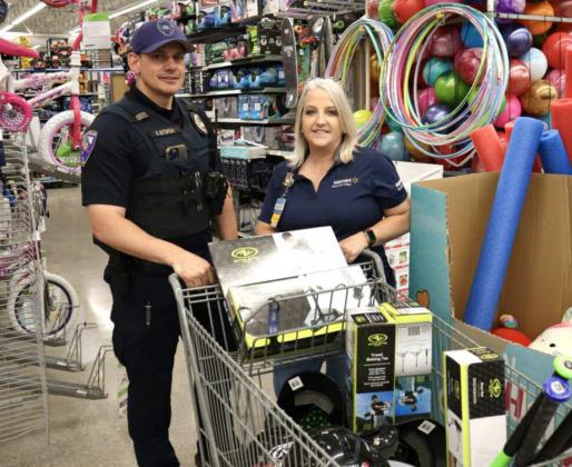 Milan Police Chief Carl Ustupski (left) and Walmart Front End Coach Jennifer Beard (right) prepare for checkout after MPD partnered with Walmart to update Milan’s youth tee-ball league’s equipment, including helmets, tees, bats, and balls. Kylie Garcia - CC