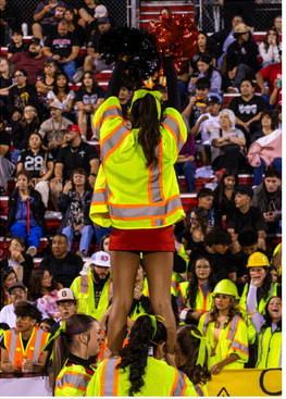 Chloe Marquez, senior, performs a cheer stunt while wearing a construction-themed safety vest during the Pirates’ football game at Grants High School on Aug. 28, 2026. Photo by Jay Langford