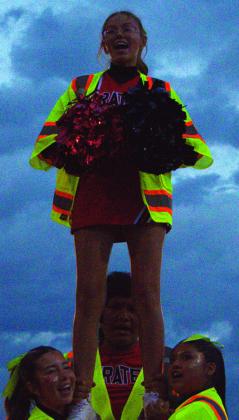 Jay Langford- Student Journalist Amber Asplund, junior, performs on the sideline during a rainy Grants High School football game. Wearing goggles as rain falls across the field, Amber cheers on the Pirates alongside her teammates