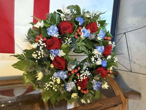 A red, white and blue wreath designed by Grants FFA members stands beside the American flag inside the Double Six Art Gallery during a Veterans Day luncheon honoring local service members. Courtesy Photo